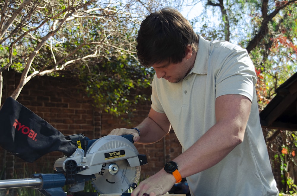 a man using a circular saw to cut a piece of wood