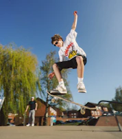 Street-level view of a skateboarder mid-trick, sporting a bright, oversized t-shirt from our collection.
