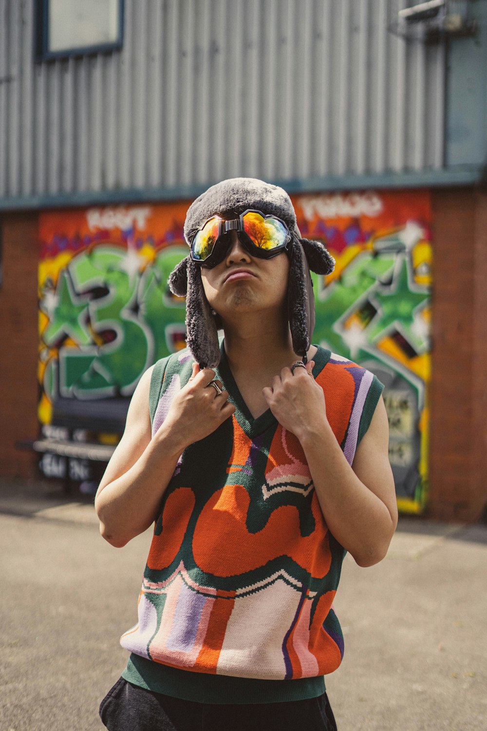 a person wearing a hat and sunglasses standing in front of a building