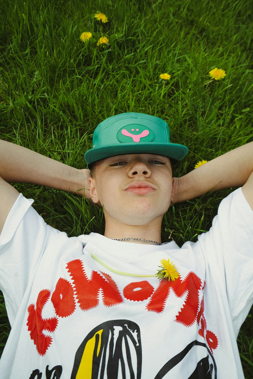 a boy laying in the grass wearing a green hat