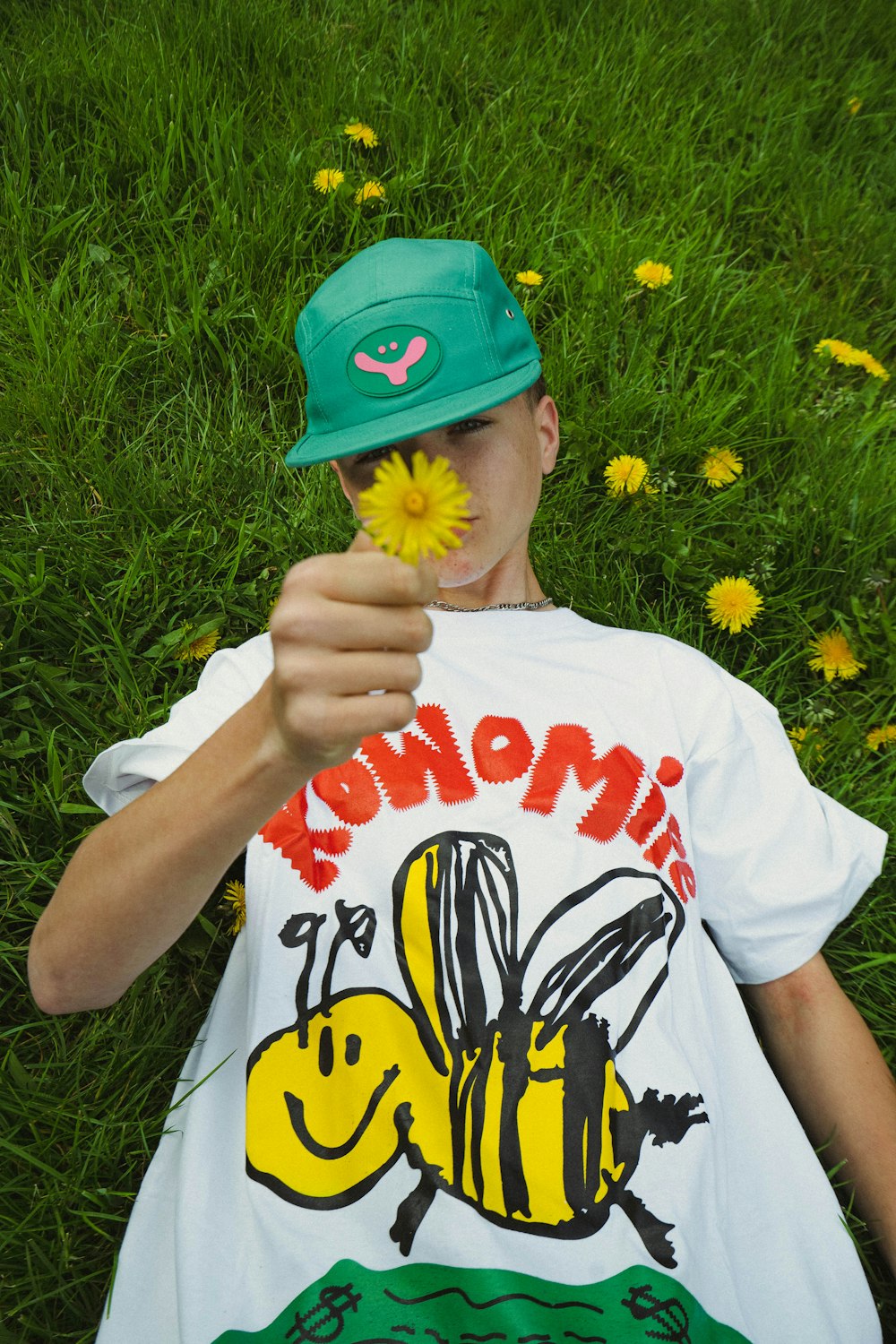 a boy laying in the grass with a flower in his hand