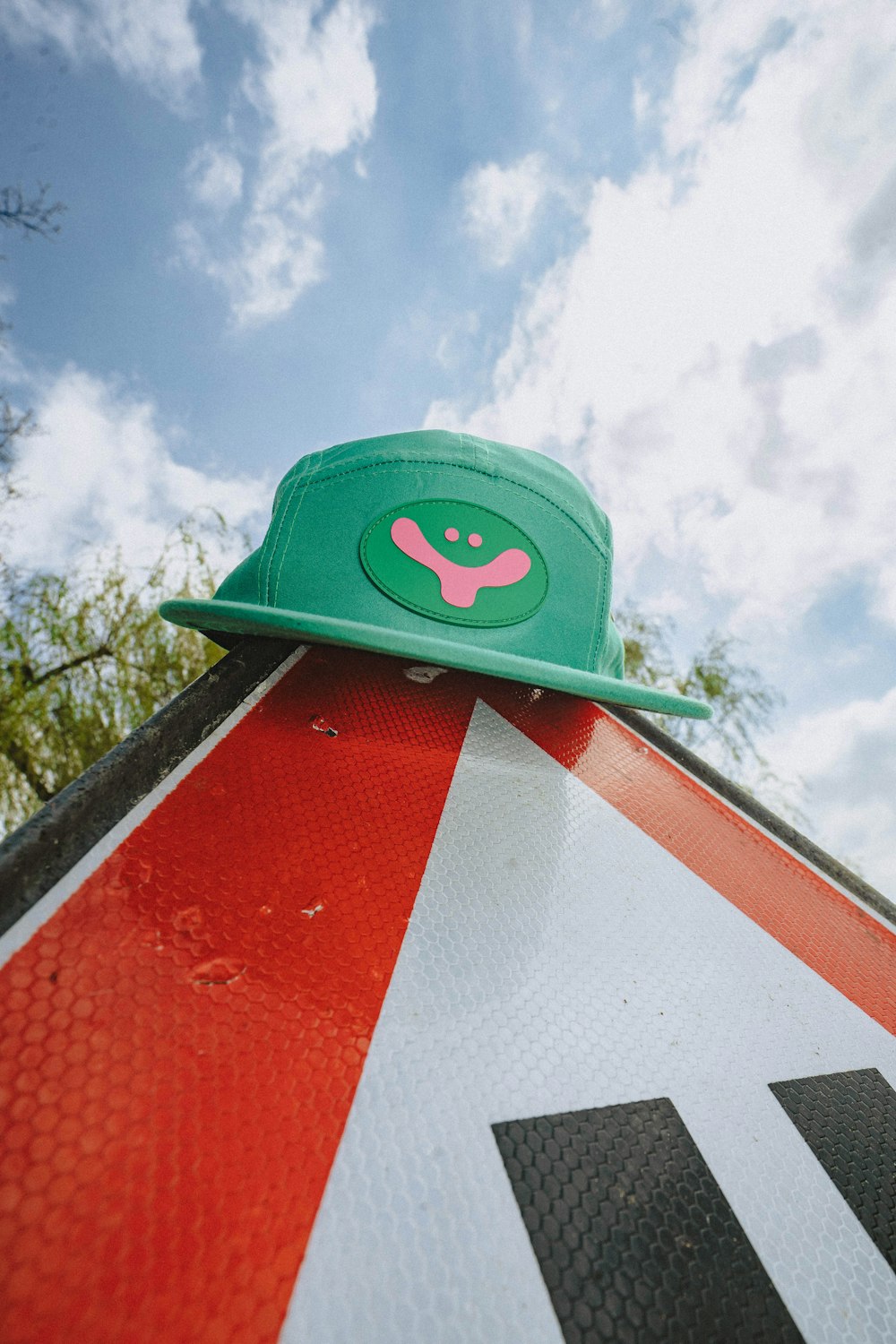 a green hat sitting on top of a red and white sign
