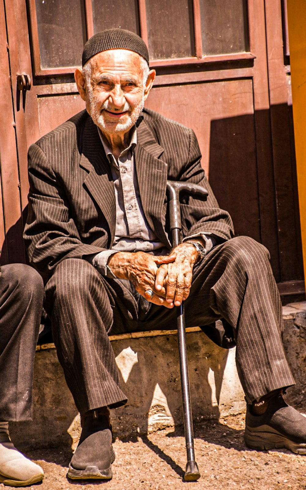 an old man sitting on a bench with a cane