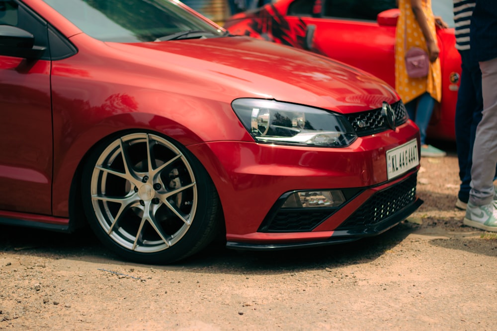 a red car parked in front of a group of people