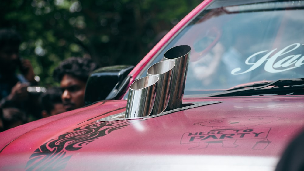 a close up of a red car with people in the background