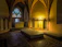 A warm, sunlit chapel interior with colorful stained glass windows and wooden pews.