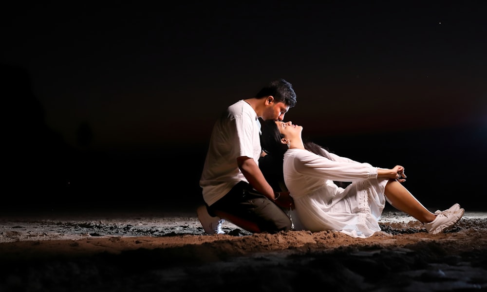 a man kneeling down next to a woman on a beach