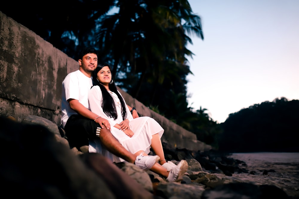 a man and a woman are sitting on a rock