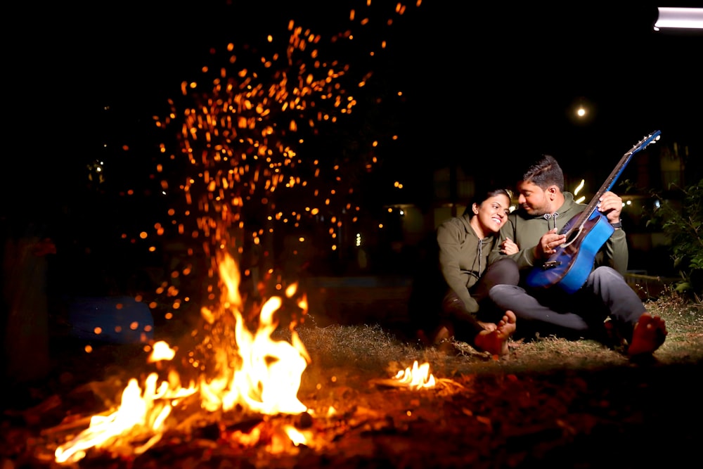 a man and a woman sitting in front of a fire