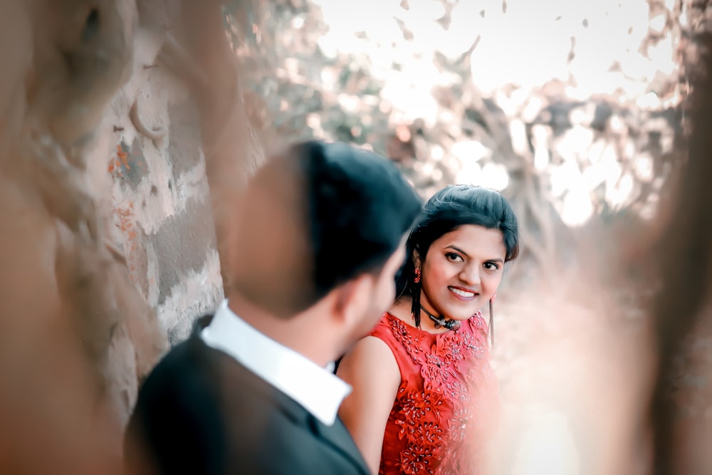 a woman in a red dress standing next to a man