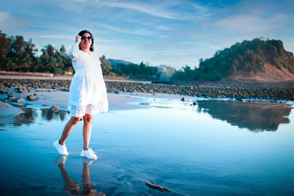 a woman in a white dress standing on a beach