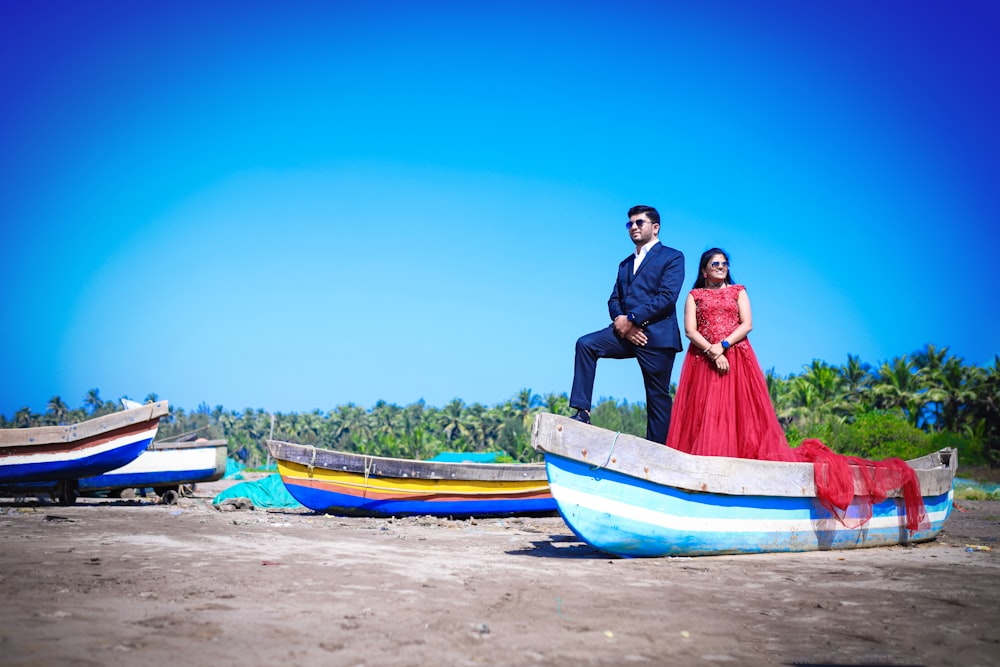 a man and a woman in a red dress standing on a boat