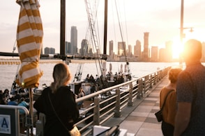 a group of people standing on a pier next to a body of water