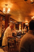 A bartender serving drinks in a warm, inviting bar setting.