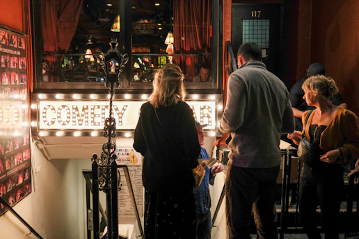 Comedians performing an interactive sketch for a small, engaged audience at a private event.