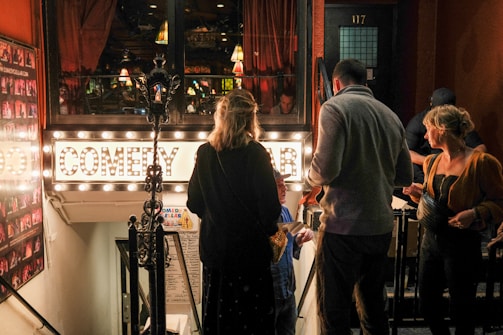 A lively crowd enjoying a stand-up comedy show at Bixiga Comedy, with warm lighting and a visible bar in the background.
