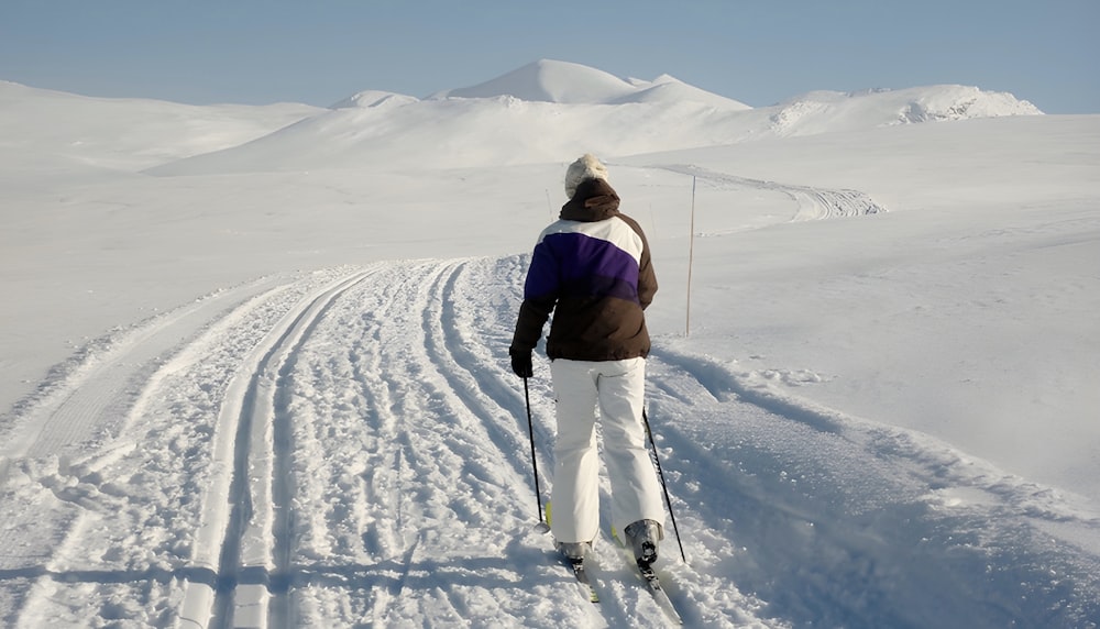 雪に覆われた斜面をスキーで下る男性