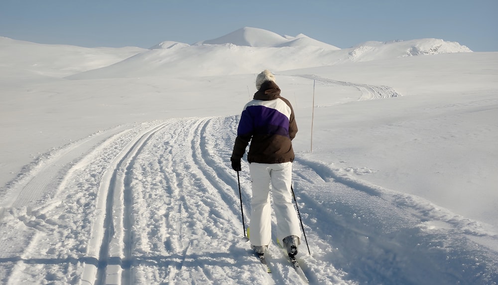 um homem andando de esqui por uma encosta coberta de neve