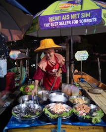 a woman wearing a yellow hat standing in front of a table filled with food