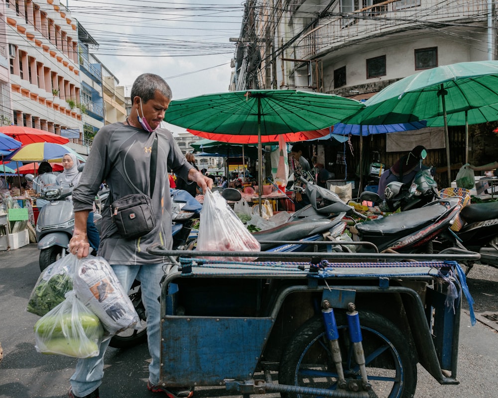 a man walking down a street carrying bags of produce