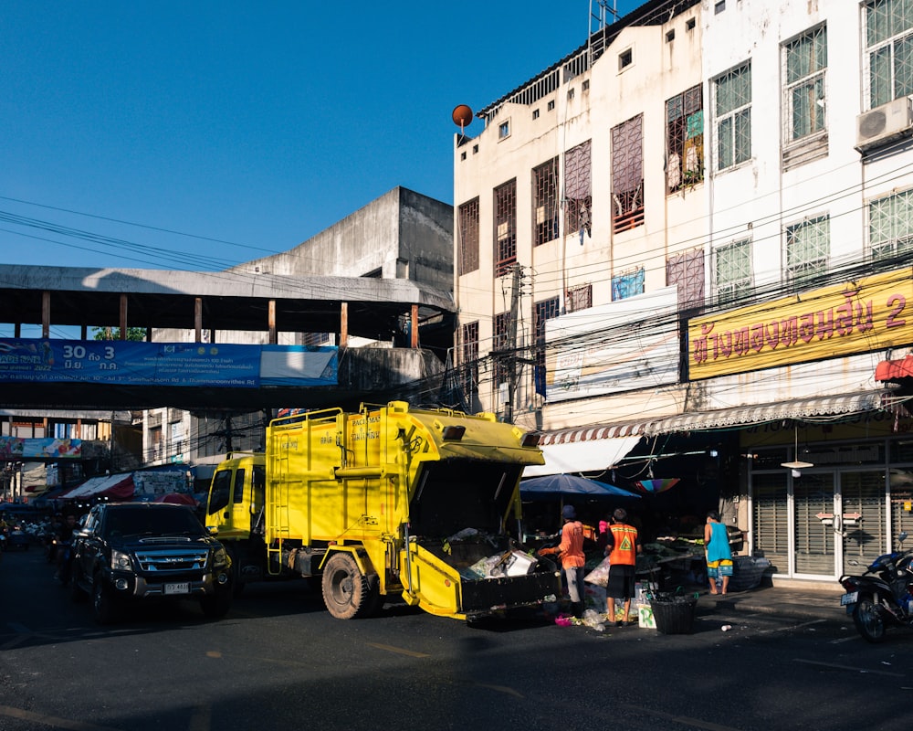 a yellow garbage truck parked in front of a building
