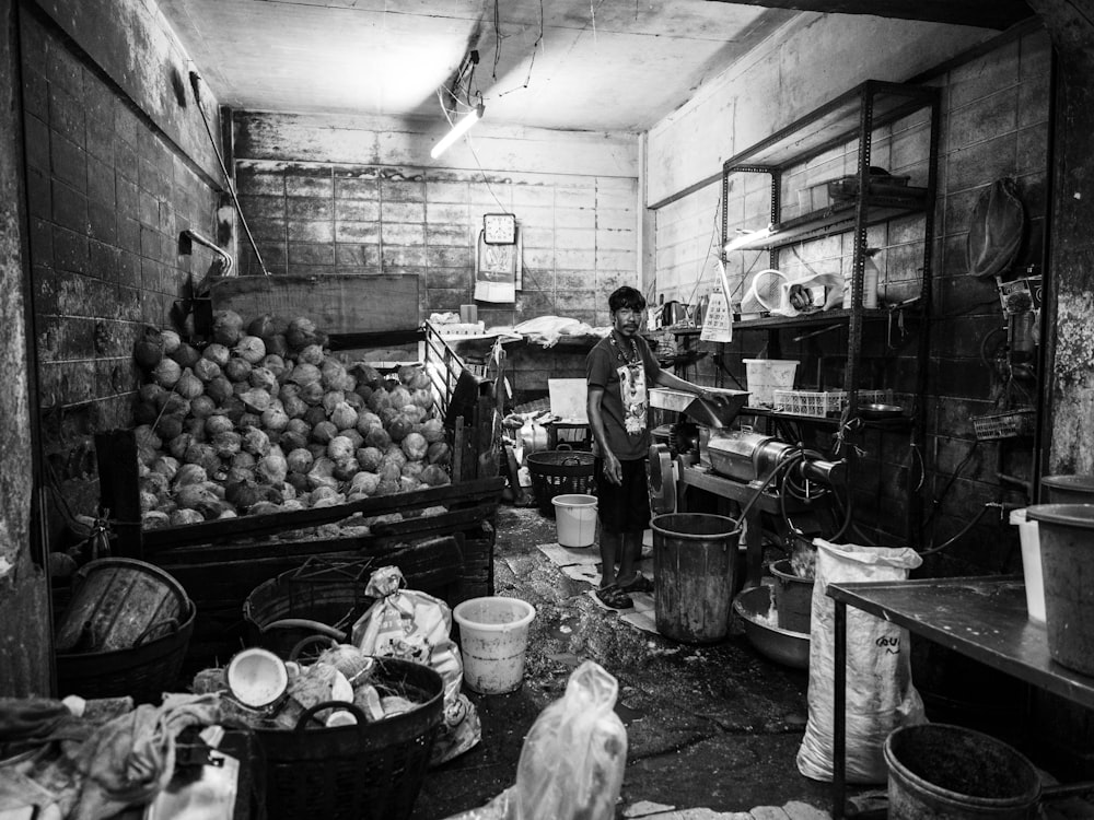 a black and white photo of a man standing in a kitchen