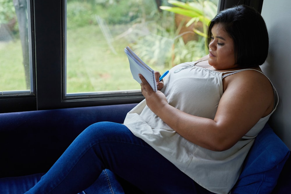 a woman sitting on a couch reading a book