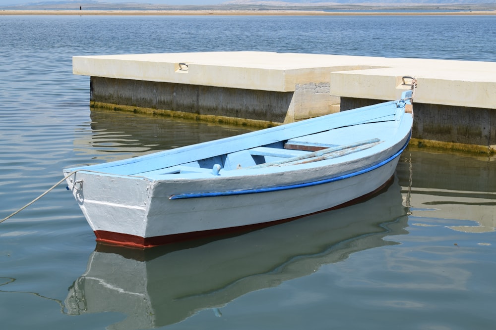 a small blue and white boat tied to a dock