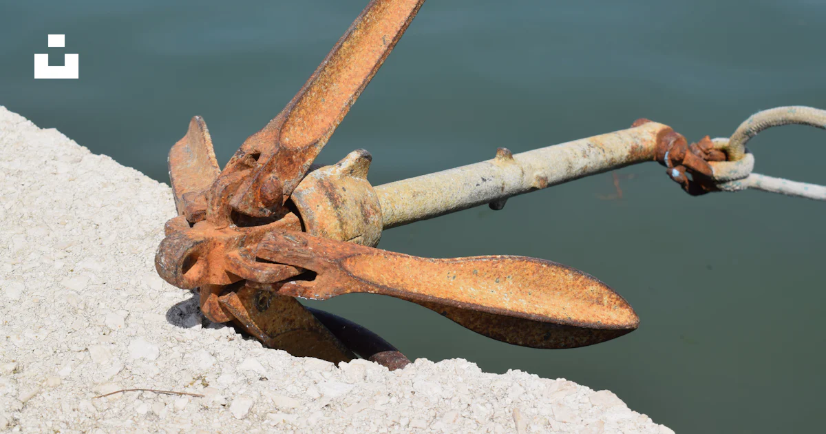 A rusted metal object sitting on the side of a body of water photo ...