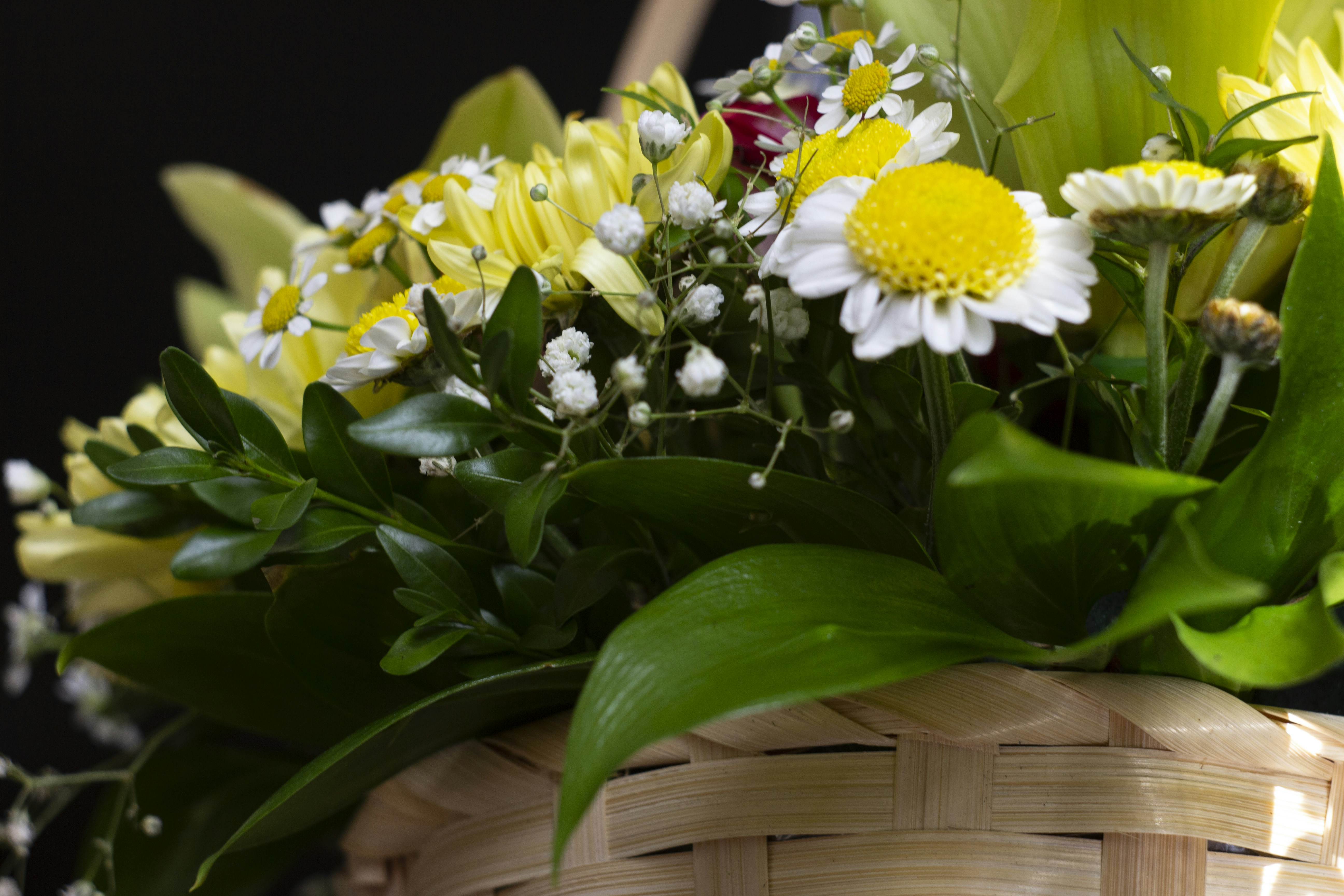 Una canasta llena de muchas flores encima de una mesa