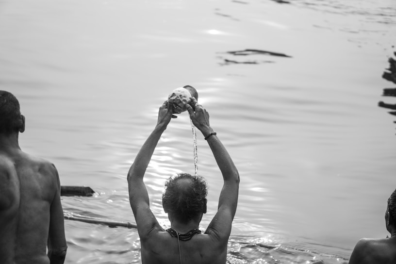 a man holding a shell above his head in the water