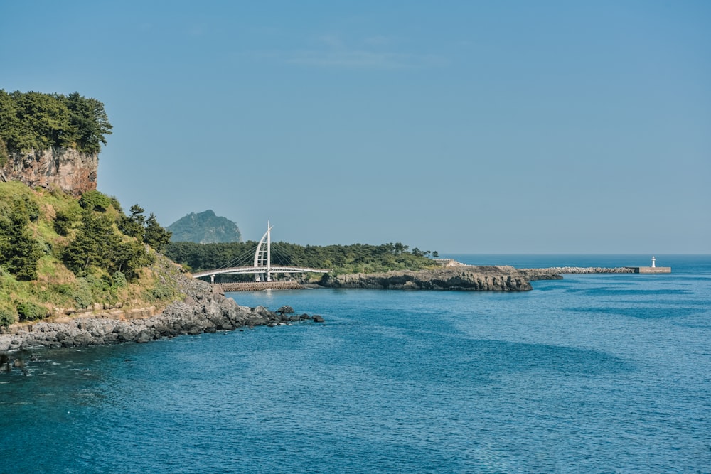 a bridge over a body of water next to a lush green hillside