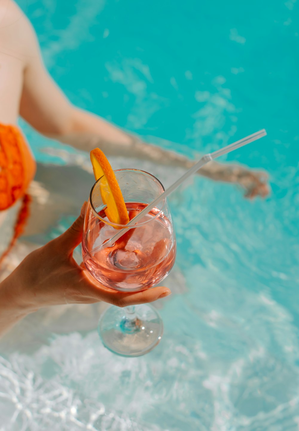 a person holding a drink in a pool