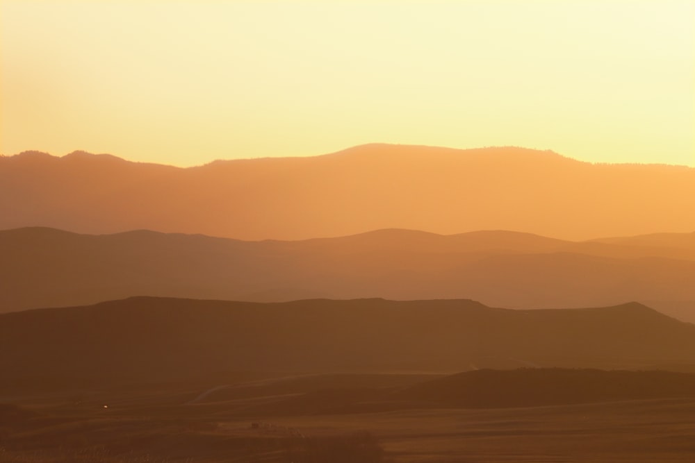 the sun is setting over the mountains in the distance