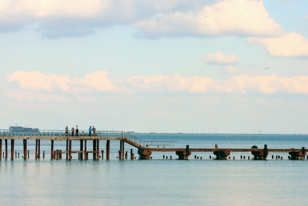 a pier with people standing on it in the water