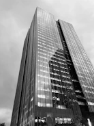 Construction progress of a commercial office tower with glass facade reflecting the sky.