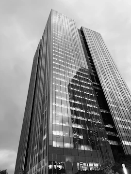 Construction progress of a commercial office tower with glass facade reflecting the sky.