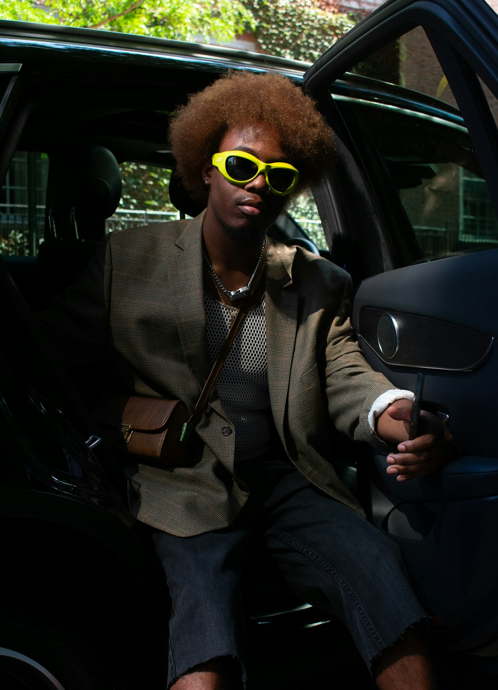 a man in a suit and sunglasses sitting in a car