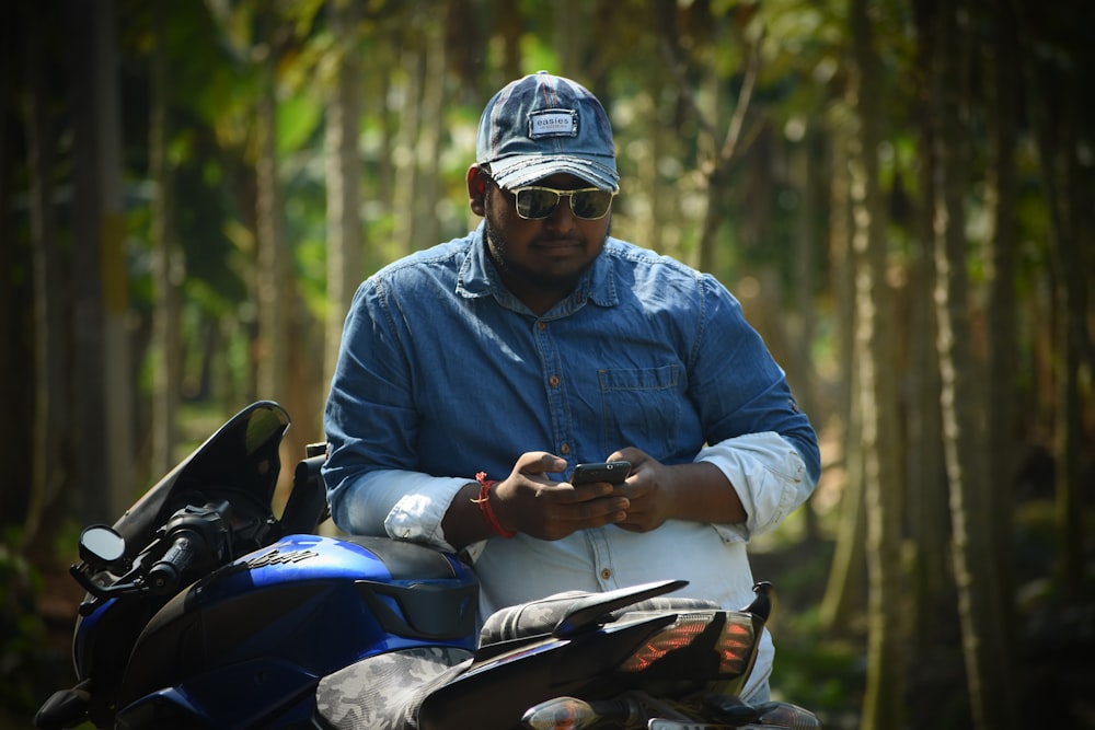Un uomo in piedi accanto a una moto che tiene un telefono cellulare