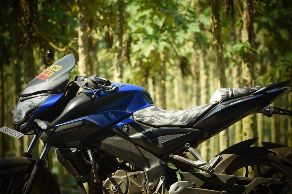 a blue motorcycle parked in front of a forest