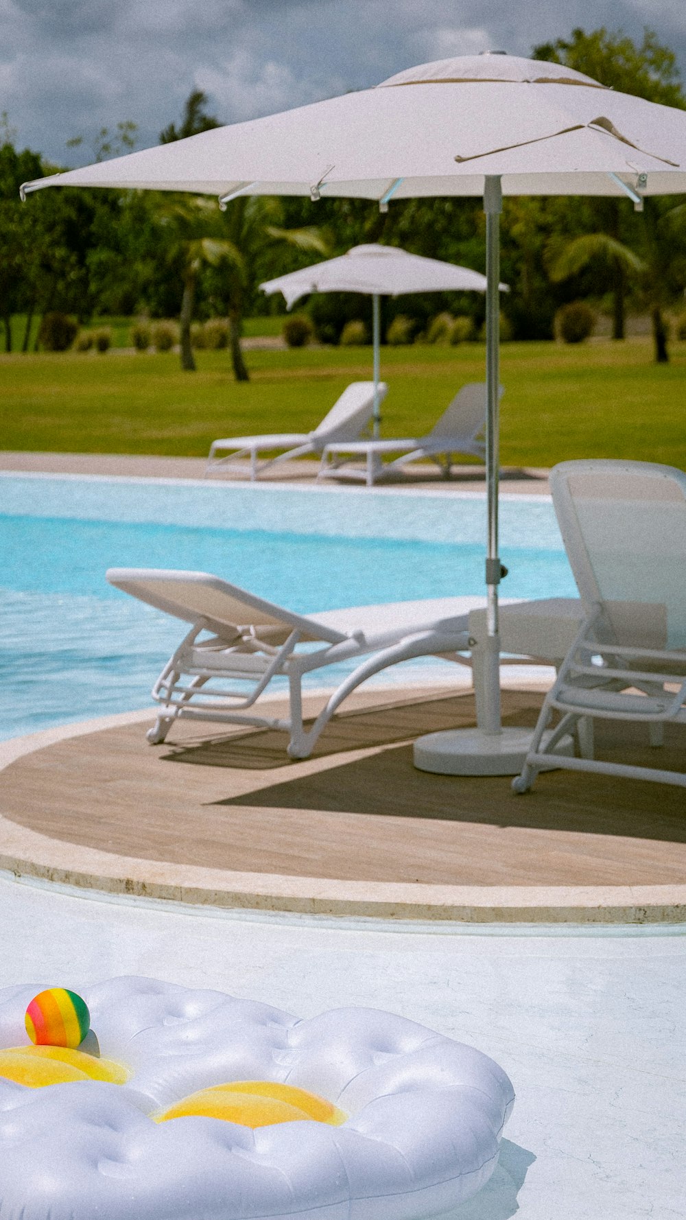 a pool with an inflatable ball and lounge chairs