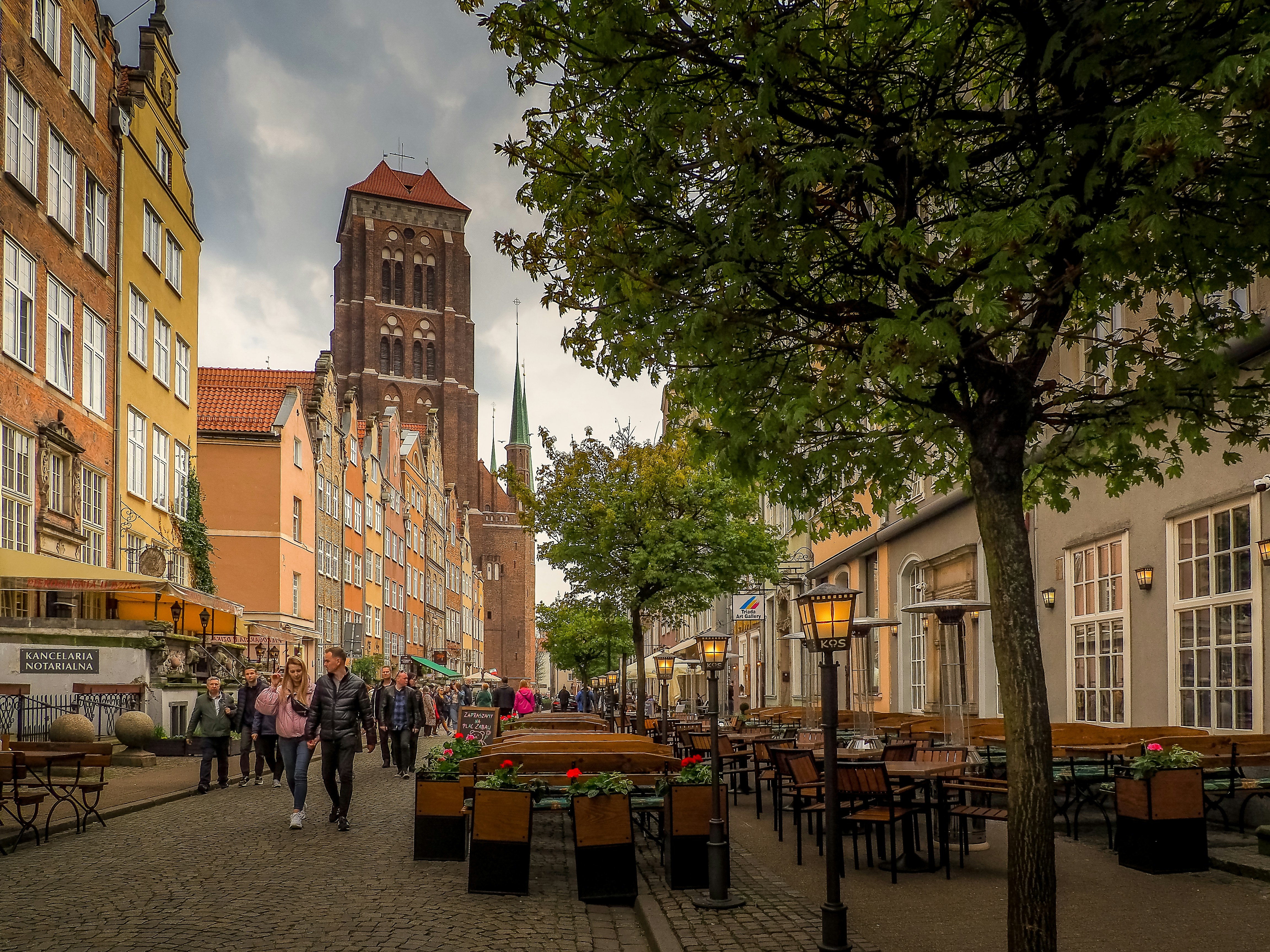 a group of people walking down a street next to tall buildings