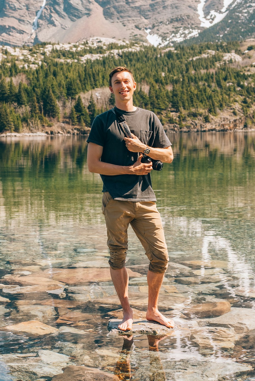 a man standing on a rock in front of a lake