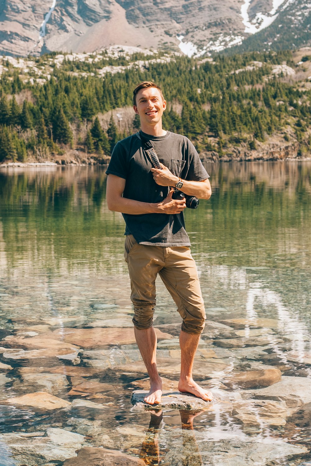 Un uomo in piedi su una roccia di fronte a un lago