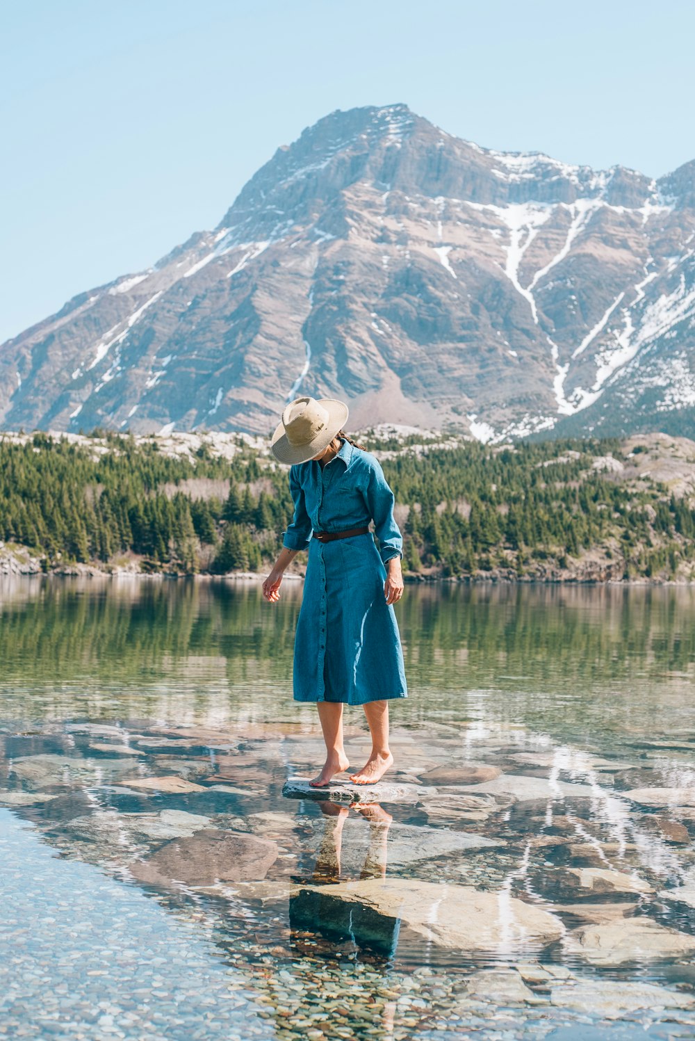 a woman standing on a rock in front of a mountain