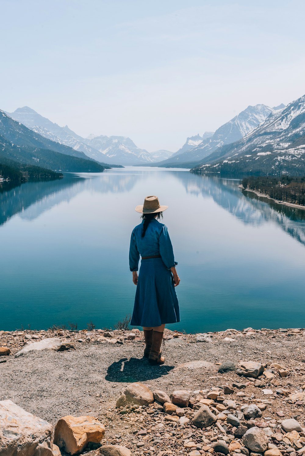 a woman in a hat looking out over a lake