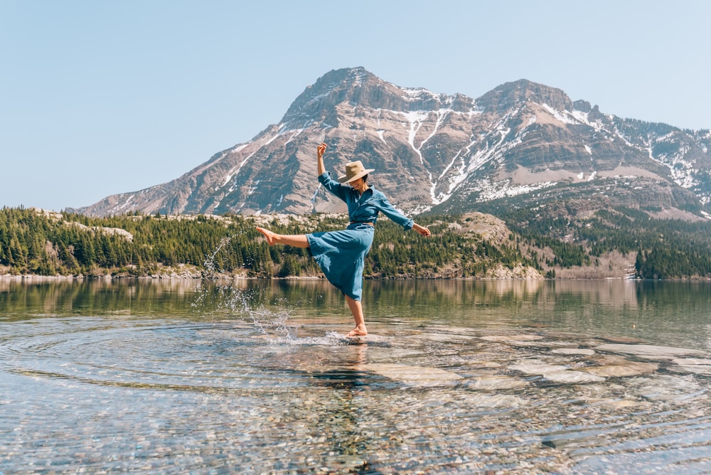 a woman standing on a rock in the middle of a lake
