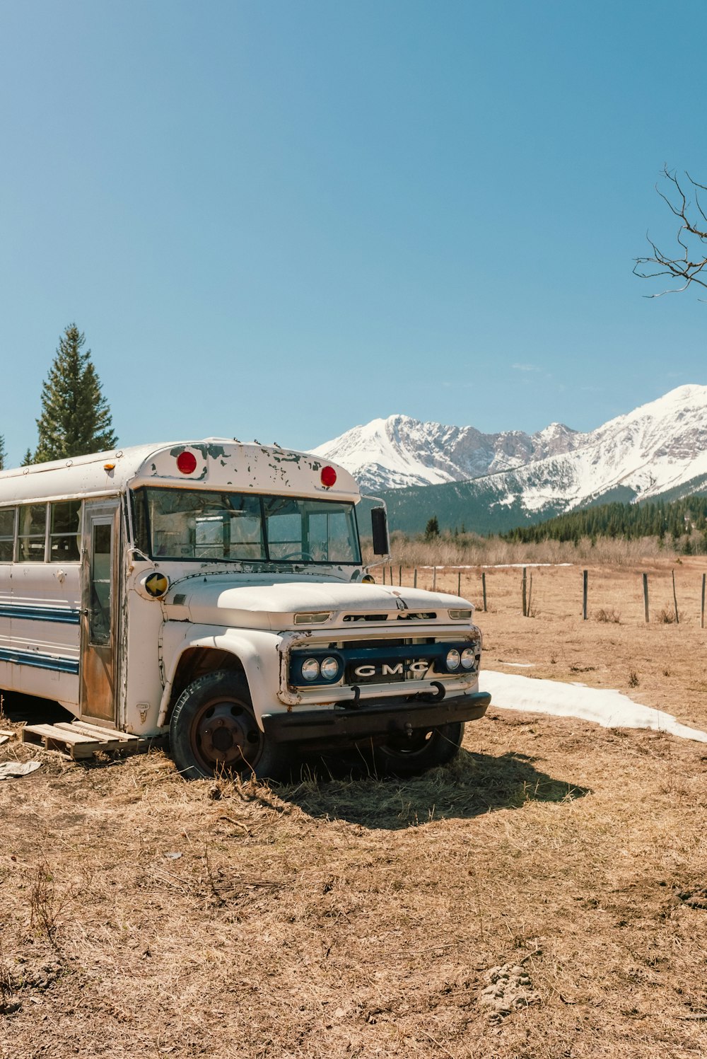 Un autobus scolaire garé dans un champ avec des montagnes en arrière-plan