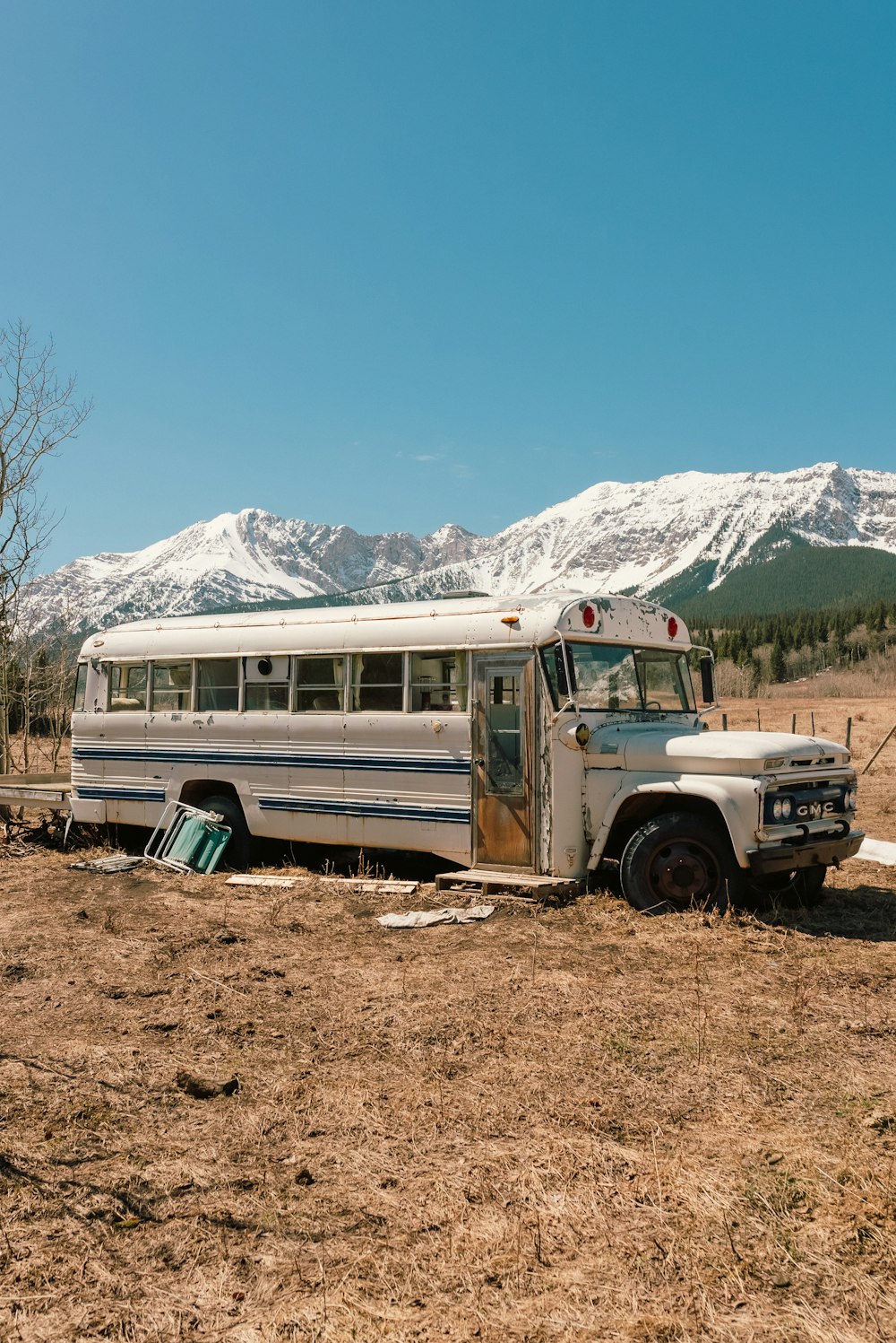 um ônibus velho sentado em um campo com montanhas ao fundo