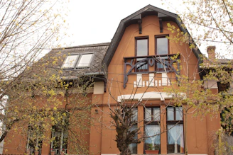 A skilled painter carefully applying a rich whitetail brown coat to the exterior of a cozy home nestled among trees.